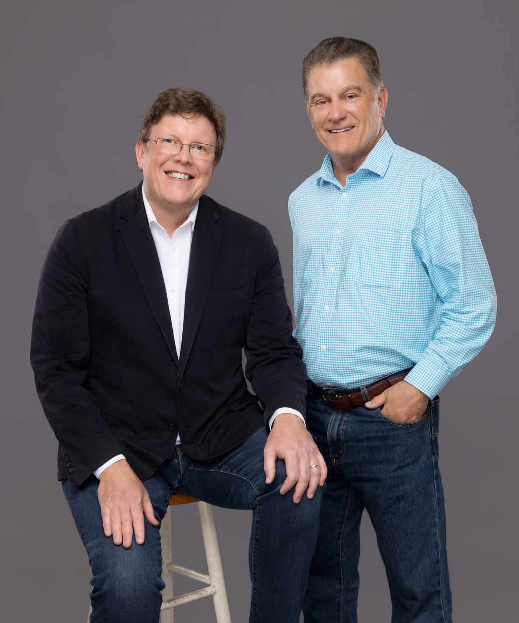 Two men posing for a photo in front of a background.