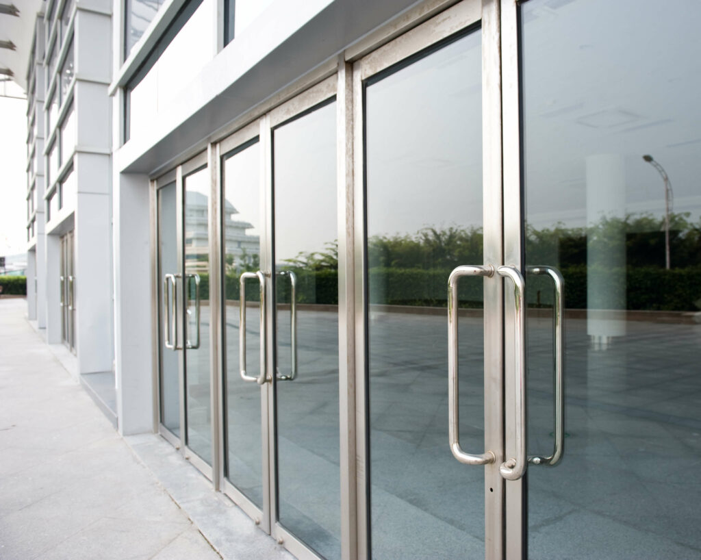 A row of sleek glass double doors with metal frames and handles adorns the exterior of the modern building.