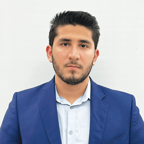 Santiago Ortega, a man with short dark hair and a beard, is wearing a blue suit jacket over a light blue shirt, standing against a plain white background.